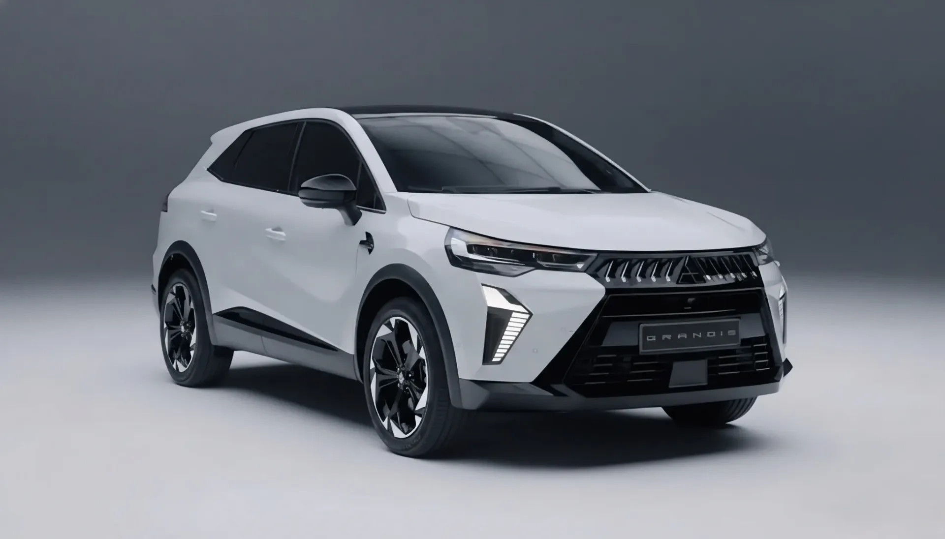 A dianteira exibe o design "Dynamic Shield" da Mitsubishi Motors, distinguido por uma grelha preta brilhante e detalhes em prata acetinada, transmitindo uma sensação de confiança e elegância.
